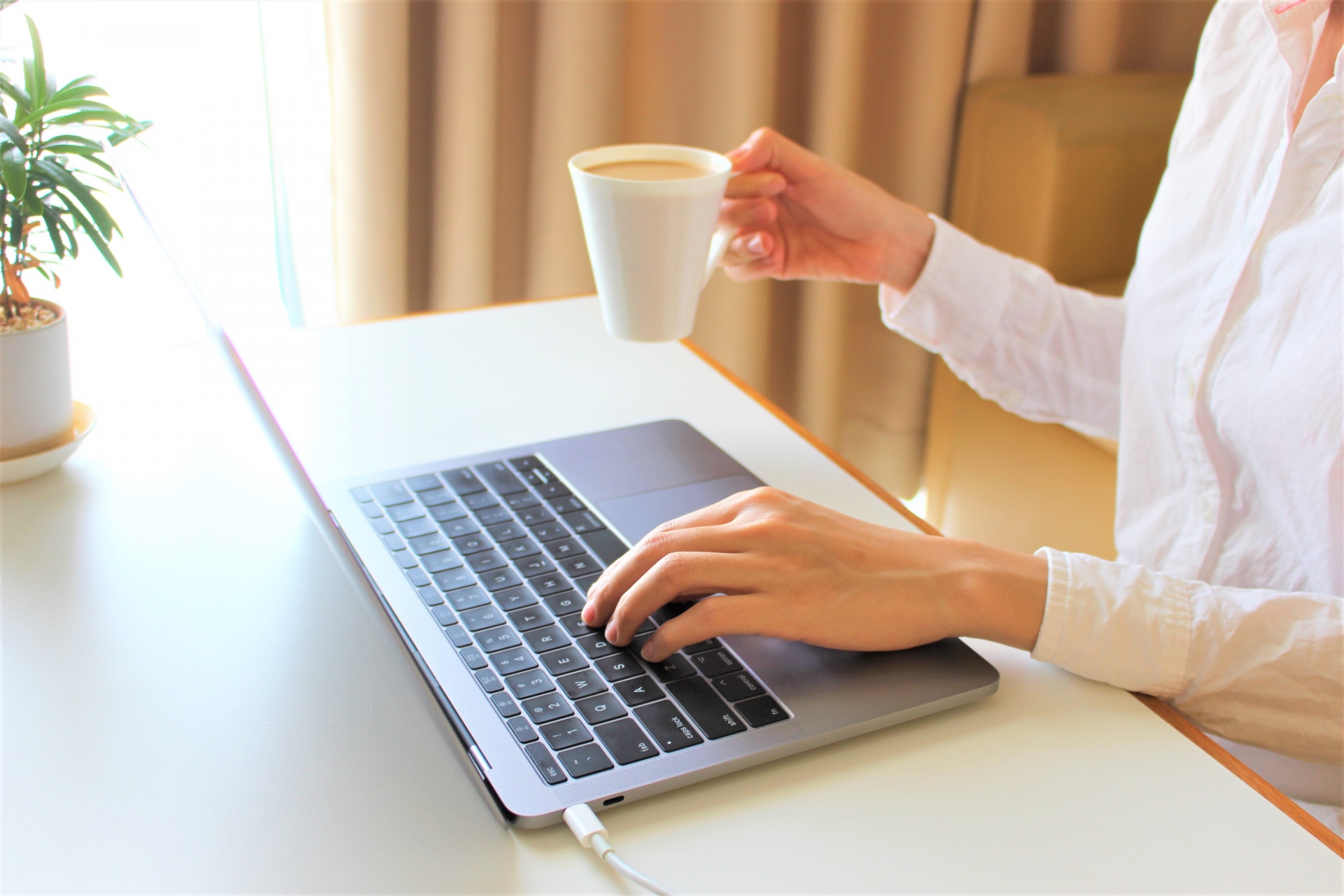 コーヒー片手にパソコンを触る人