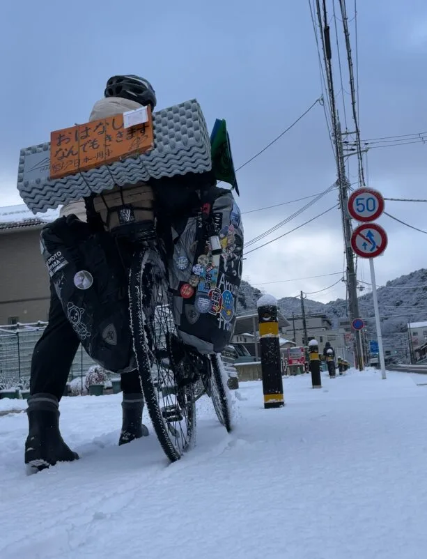 雪の中自転車を押す旅人