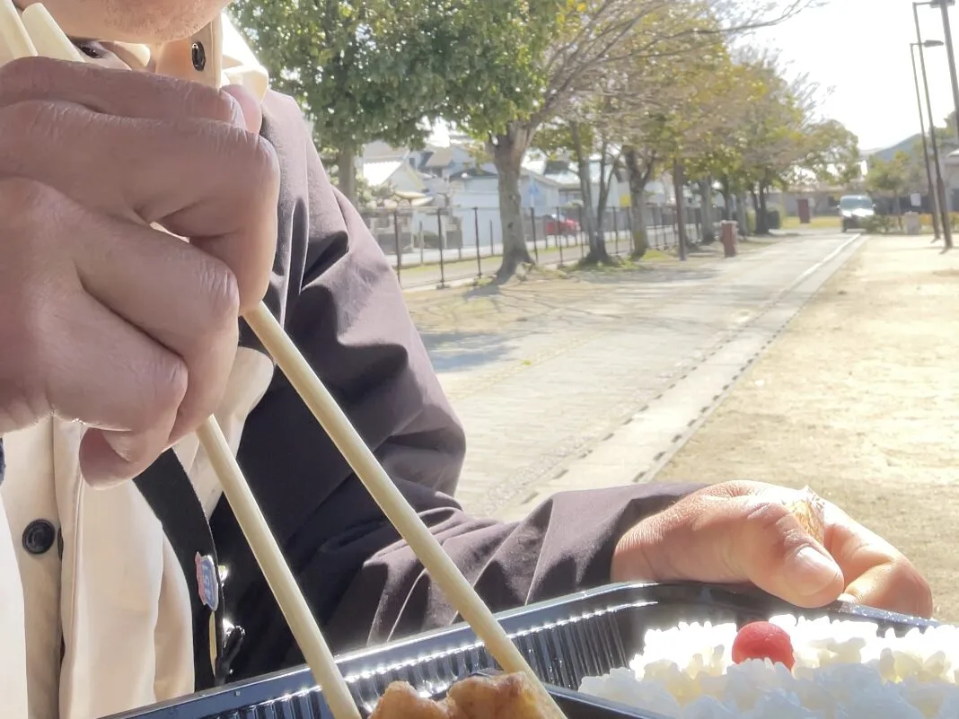 公園で唐揚げ弁当を食べる旅人