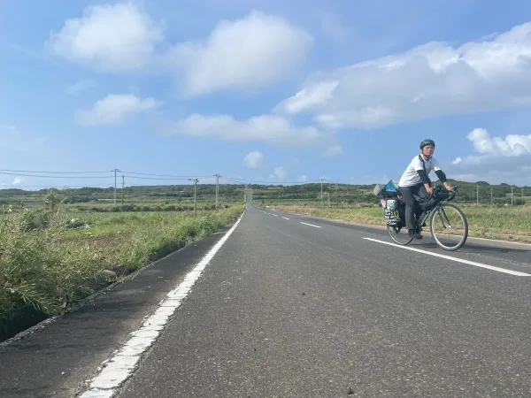 サトウキビの一本道で自転車と記念写真