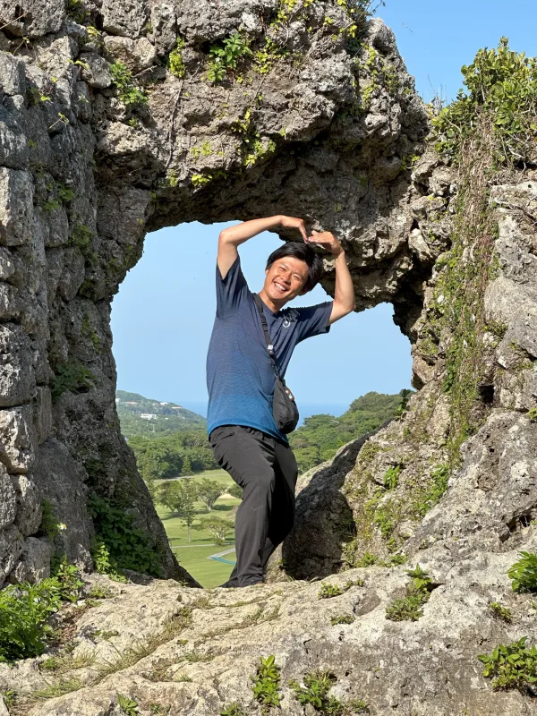 玉城グスクの石垣のハートの穴でポーズする旅人