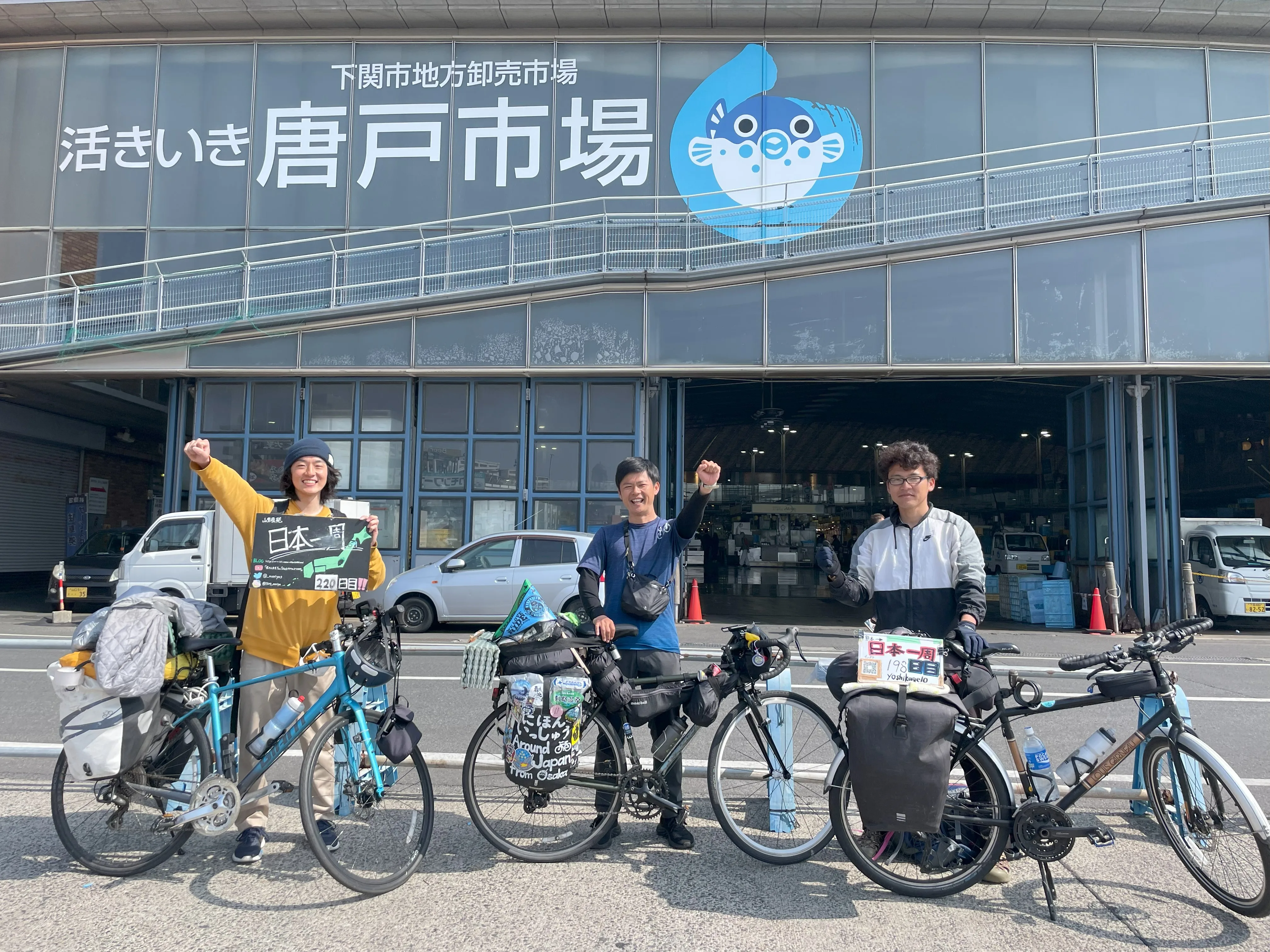 唐戸市場前で写真を撮る自転車日本一周中の旅人たち