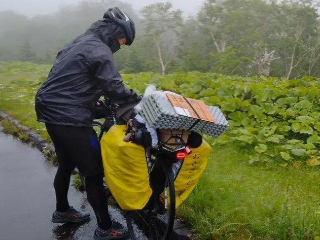北海道で雨にあたる自転車日本一周中の旅人